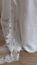 Load and play video in Gallery viewer, White wedding dress with a long lace veil in front of a white curtain.
