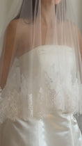 Load and play video in Gallery viewer, Bride wearing a white wedding dress with a lace veil against a white curtain background.
