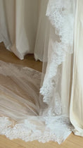 Load and play video in Gallery viewer, Bride wearing a white wedding dress with a lace veil against a white curtain background.
