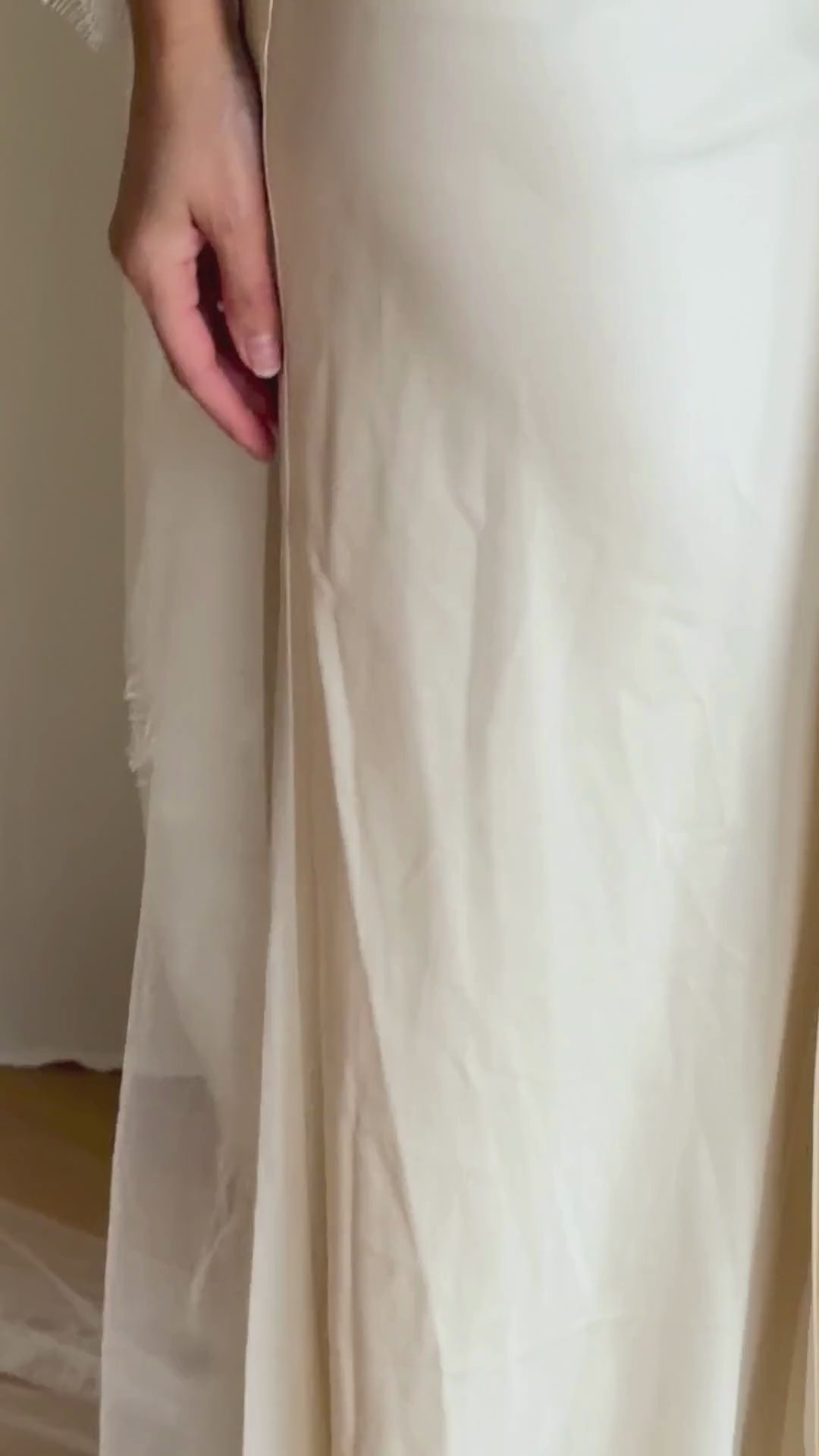 Bride wearing a white wedding dress with a lace veil against a white curtain background.