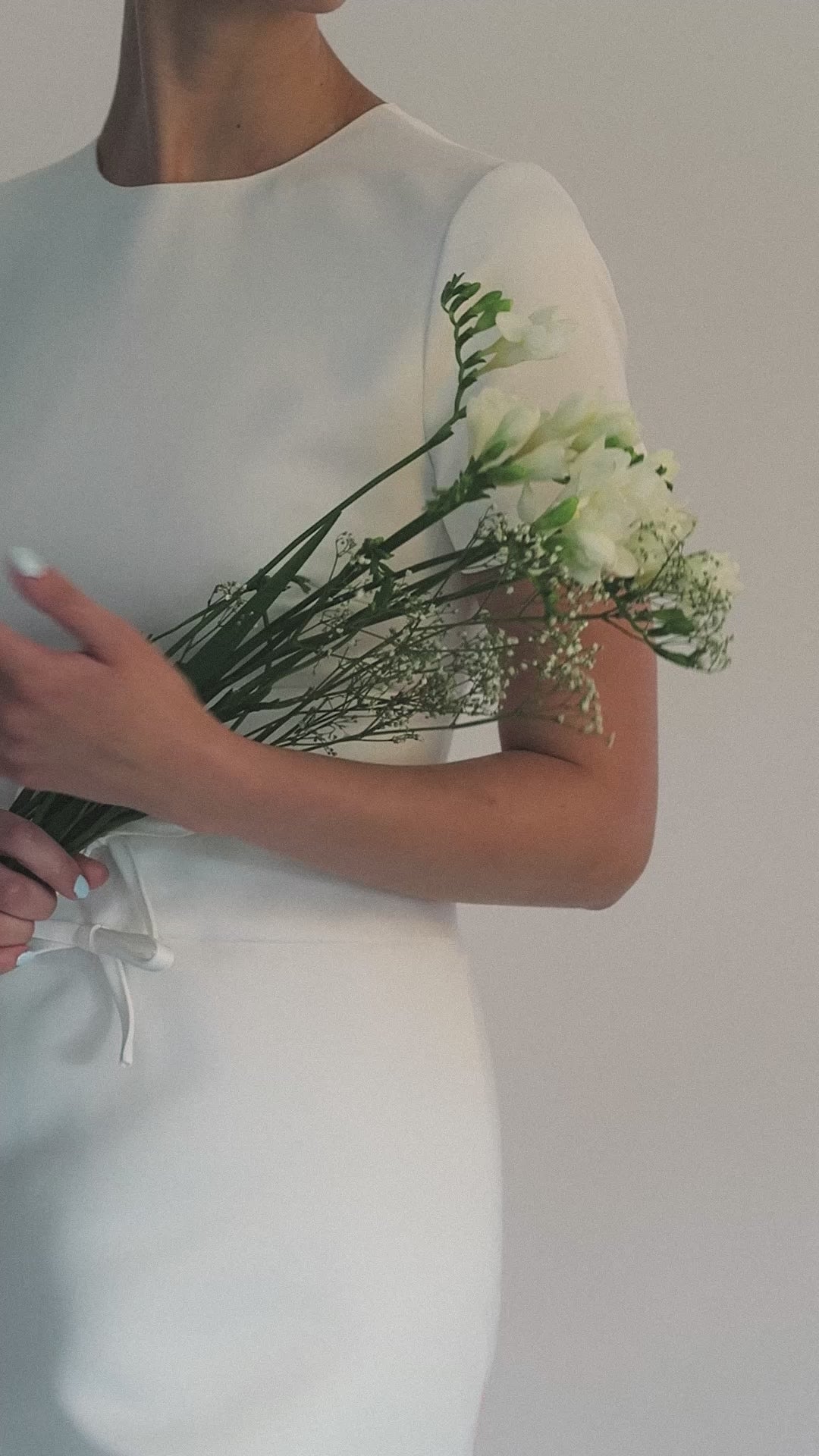 Woman wearing a white bridal headband against a light grey background