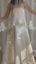 Load and play video in Gallery viewer, Bride wearing a white wedding dress with a lace veil against a white curtain background.
