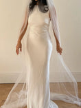 Load image into Gallery viewer, Person wearing a white wedding dress with a long plain veil against a plain background
